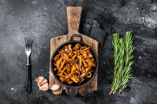 Franse geroosterde cantharelpaddestoelen met uien en thyme in een pan. zwarte achtergrond. bovenaanzicht.