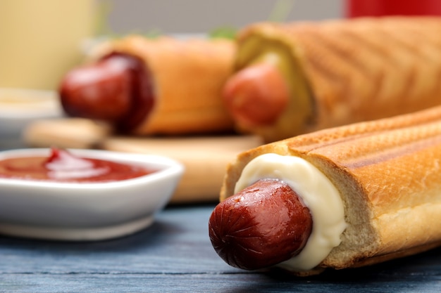 Franse hotdogs. Lekkere hotdogs op het bord en saus op een blauwe houten tafel. fastfood straatvoedsel. worstjes op een broodje.