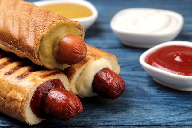 Franse hotdogs. Lekkere hotdogs op het bord en saus op een blauwe houten tafel. fastfood straatvoedsel. worstjes op een broodje.