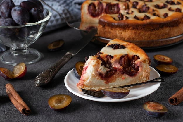 Franse kwarktaart met pruimen klaar om te eten op een bord op een grijze tafel Close-up