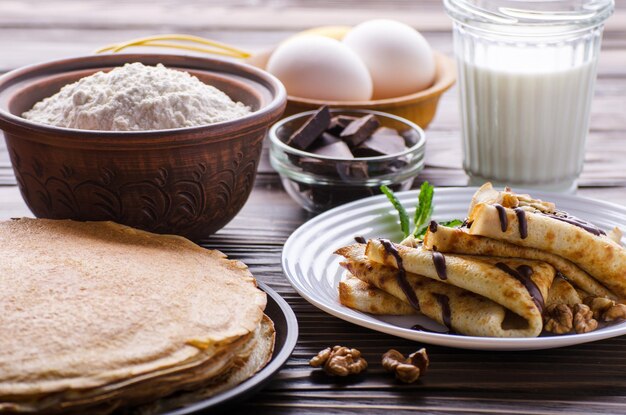 Franse pannenkoeken met chocoladesaus, walnoten, eieren en bloem op houten keukentafel