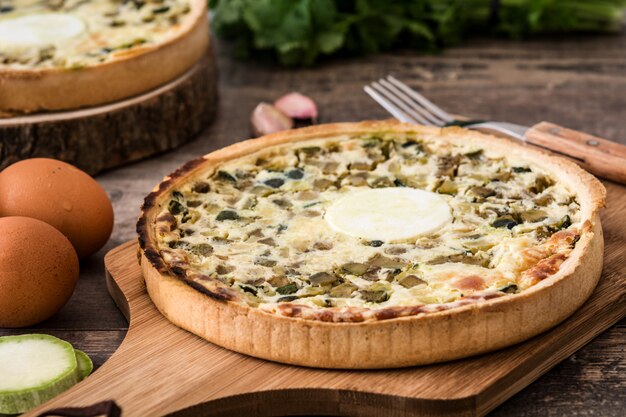 Franse quiche Lorraine met groenten op een rustieke houten tafel