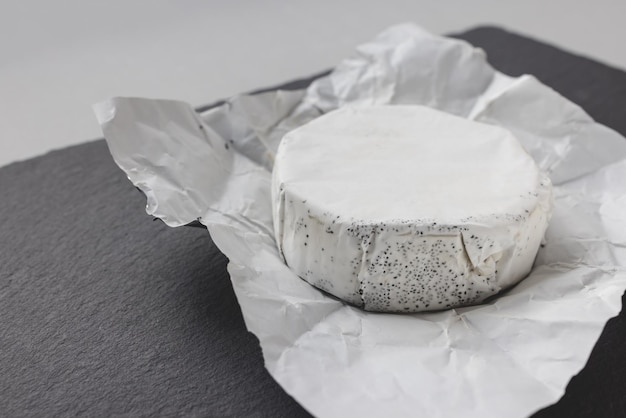 Franse ronde camembert kaas met maanzaad op zwarte leisteen plaat kopie ruimte