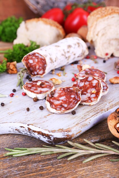 Franse salami met tomaten, peterselie en brood op snijplank op houten achtergrond