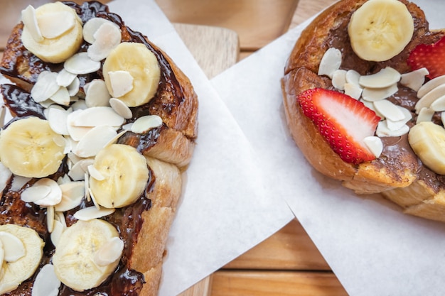 Franse toosts met de aardbei van de chocoladebanaan en amandel op de houten lijst