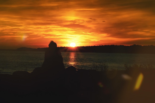 Photo frau am meer im sonnenuntergang