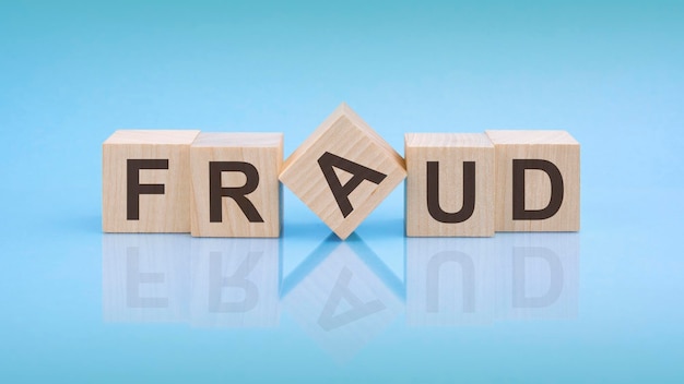 Fraud word is written on wooden cubes on a bright blue background closeup of wooden elements