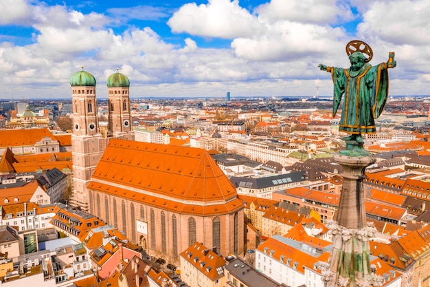 Frauenkirche surrounded by buildings under the sunlight and a cloudy sky in Munich, Germany