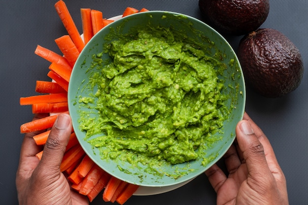 Foto avocado sfilacciato in una ciotola nelle mani dell'uomo