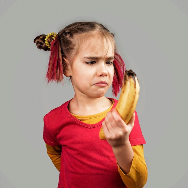 Freakish kid holds misshapen wrong color fruits and vegetables, waste food concept