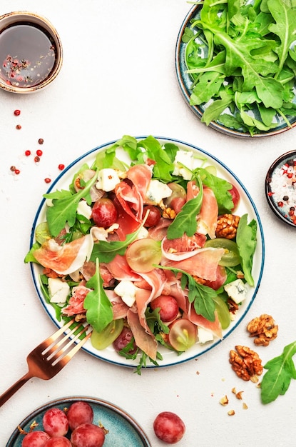 Freash grape salad with jamon blue cheese arugula nuts on white table background top view copy space