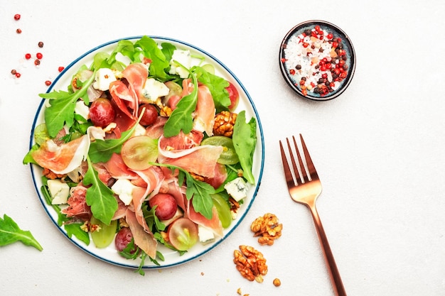 Freash grape salad with jamon blue cheese arugula nuts on white table background top view copy space