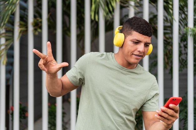 Freckled young man using smartphone and listens to music with bluetooth headphones