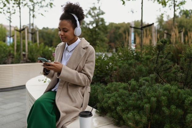 Free african girl student in headphones on the street listening to music