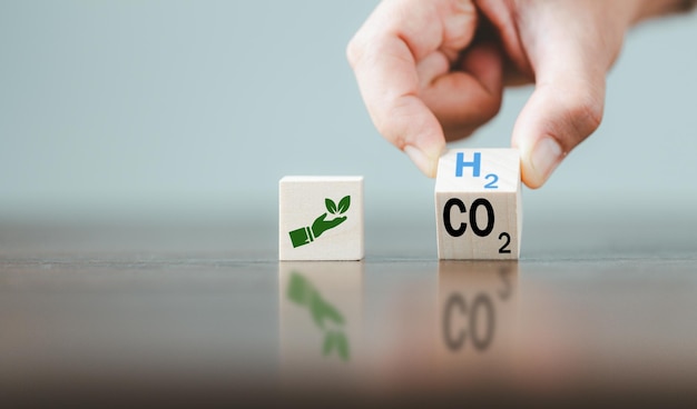 Free carbon alternative energy and global climate change\
concepts hand flipping wooden cube blocks with co2 carbon dioxide\
change to h2 hydrogen text on table background sustainable car\
energy