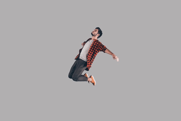 Free falling. Mid-air shot of handsome young man jumping and gesturing against background