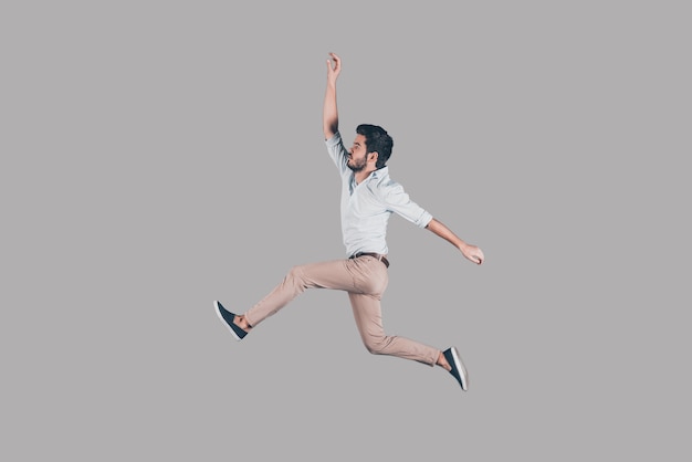 Free jumping. Mid-air shot of handsome young man jumping and gesturing against background