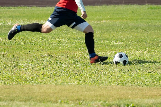 A free kick on goal in football Motion into a blur focus on the ball Foot kicking soccer ball on green grass