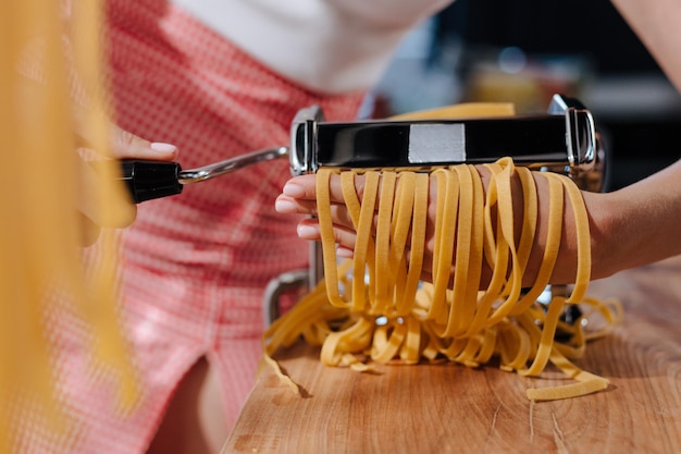 Free photo closeup person cutting pastry with machine