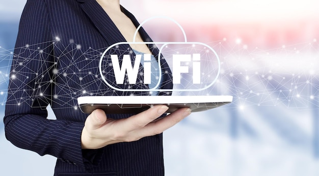 무료 WiFi 네트워크 신호 기술 인터넷 개념입니다. 밝은 배경에 디지털 홀로그램 Wi Fi 표시가 있는 흰색 태블릿을 손에 들고 있습니다. 무료 WiFi 네트워크 신호 기술 인터넷 개념입니다.