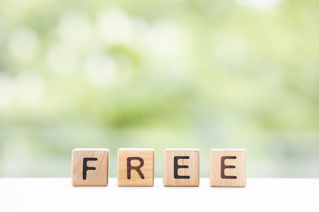 FREE word is written on wooden cubes on a green summer background Closeup of wooden elements