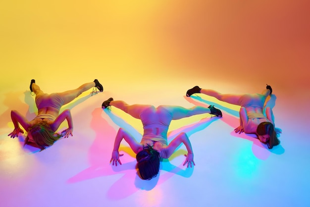 写真 動きの自由 3人の若い女性が下着を着てハイヒールで踊り グラディエントを越えて床で踊っています