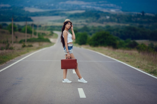 Libertà di viaggio concetto weekend estivo hipster ragazza voglia di viaggiare a piedi su strada asfaltata in terre selvagge bella ragazza con l'aspetto dell'asia meridionale