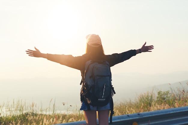 Donna del viaggiatore di libertà che si leva in piedi con le braccia alzate e godere di una bella natura