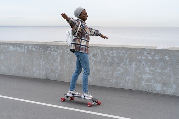 Libertà e stile di vita urbano ragazza che fa skateboard su longboard in città o sul ponte vicino al mare