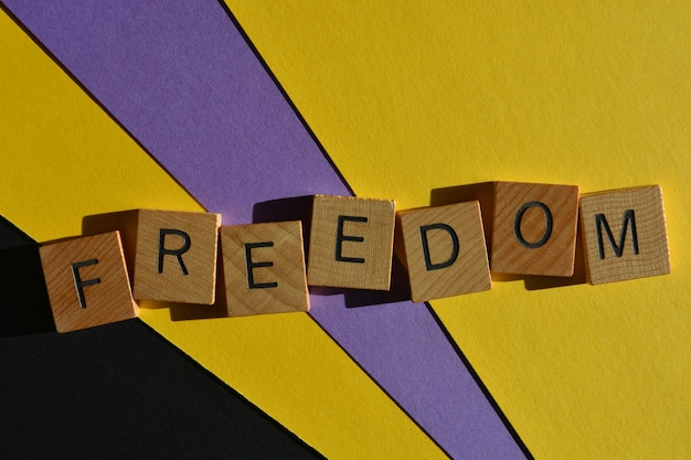 Photo freedom word in wooden alphabet letters isolated on colourful background