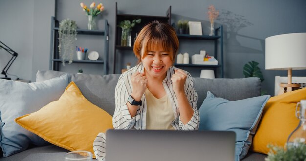 Freelance asian lady casual wear using laptop online learning in living room at house