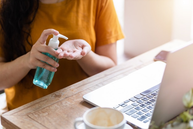 Freelance Business woman using hand put sanitizer on hand for cleaning hand to prevent virus and working with laptop