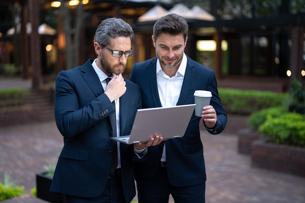 Freelance concept business men team using laptop outdoor two men talking in urban city center in bus