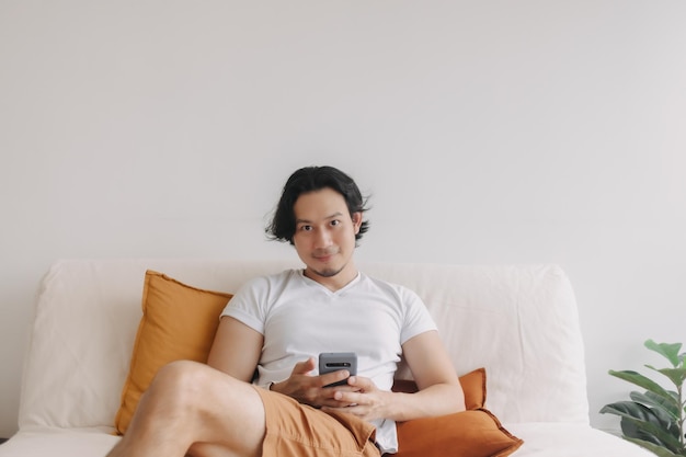 Freelance long hair man sit on the sofa and use application smartphone
