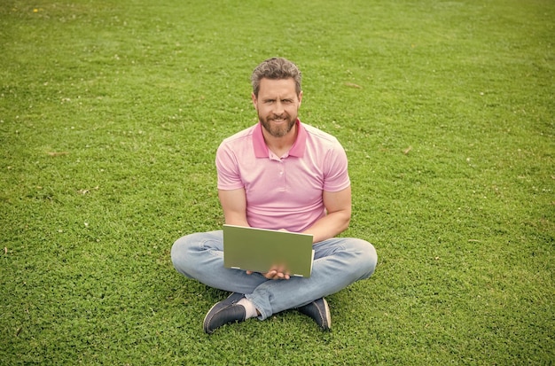 Freelance man post blog online sit on grass writing online businessman using laptop for blogging