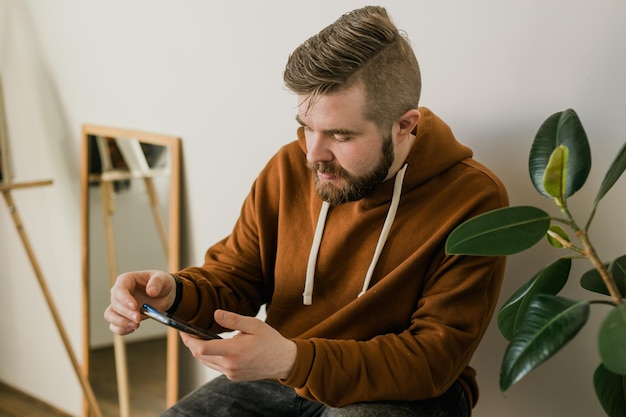 Photo freelance man using mobile phone checking social media network feed or message chat at home online digital communication and rest after hard work day