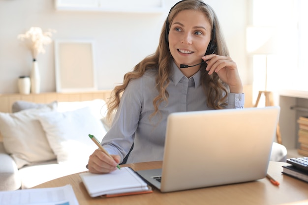 Operatore freelance che parla con le cuffie e consulta i clienti dall'home office.