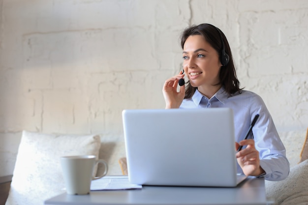 Freelance operator talking with headsets and consulting clients from home office.