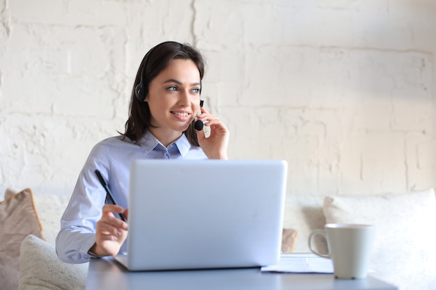 Freelance operator talking with headsets and consulting clients from home office.