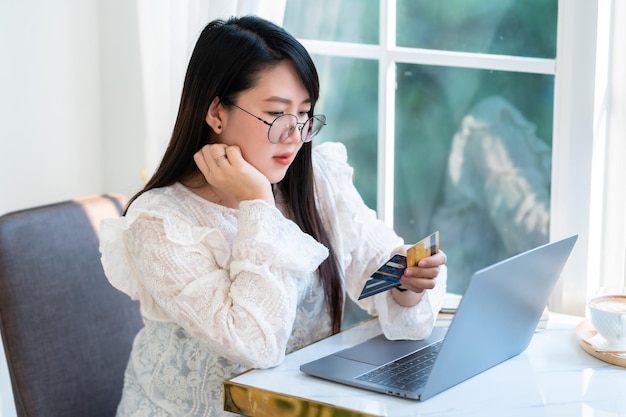 Spettacolo casual femminile d'affari di persone freelance in possesso di una carta di credito che lavora con un computer portatile in una caffetteria come lo sfondo per lo shopping online e il pagamento tramite internet