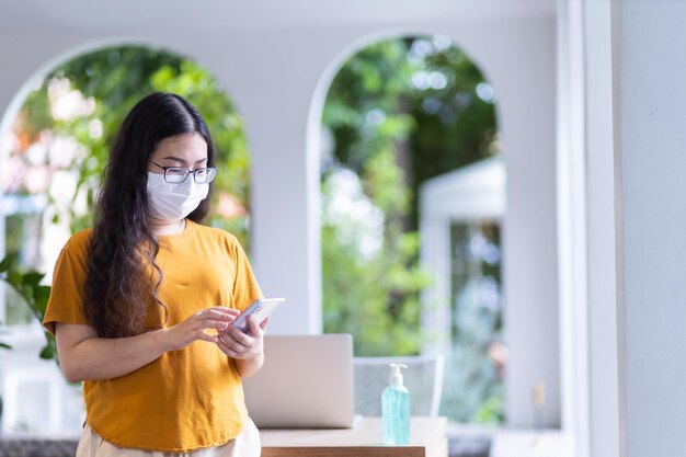 freelance people business female wearing protective mask casual and writing message on smartphone working with laptop computer working from homeConcept of Prevention of the spread of COVID19 virus