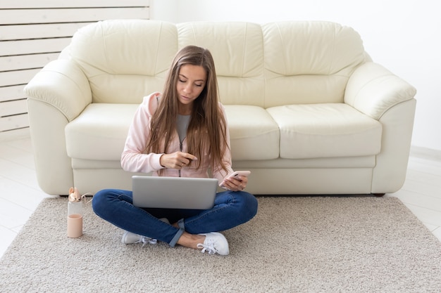 Freelance and people concept - Young woman sitting on floor and working at laptop.