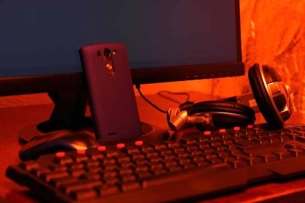 Freelance programmeur werkplek. Monitor, toetsenbord, mobiele telefoon en koptelefoon op thuisdesktop