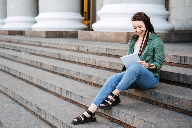 Freelance side hustle jonge vrouw hipster freelancer met tatoeage en dreadlocks die met tablet werken