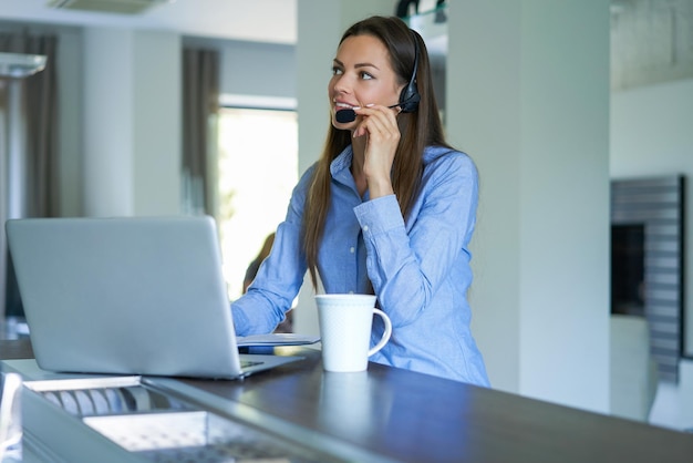 Freelance telefoniste die met headsets praat en klanten raadpleegt vanuit een thuiskantoor