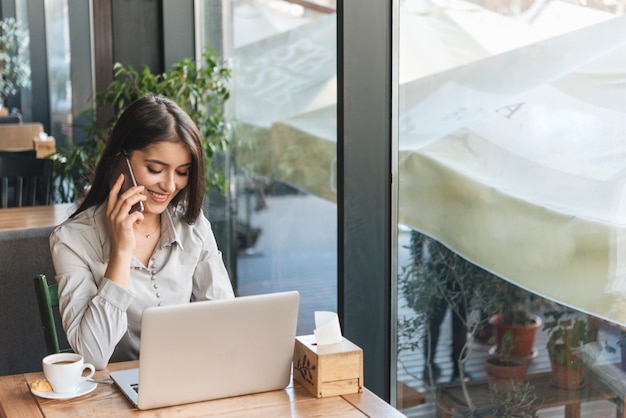 Freelance vrouw die met laptop in koffiewinkel werkt