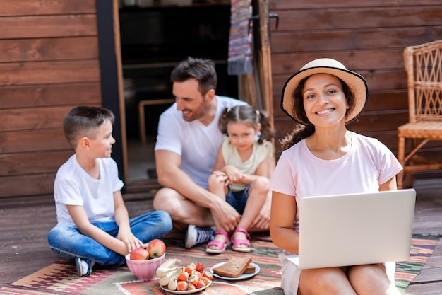 Freelance vrouw die werkt met laptop zittend op de veranda tijdens familievakantie genieten van wifi en 5g