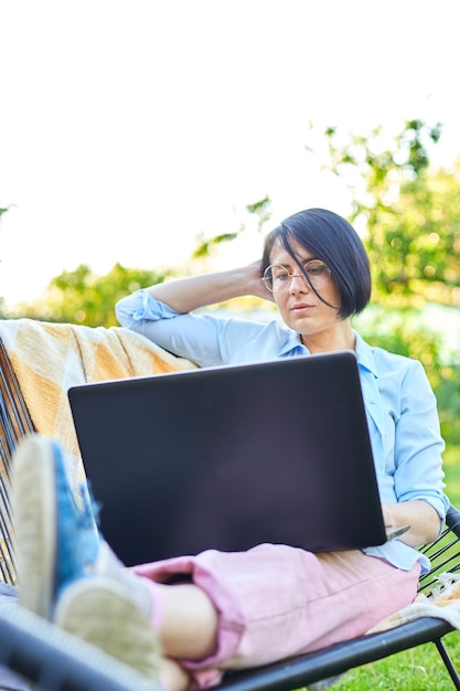 Freelance vrouw werkt op laptop thuis in de achtertuin