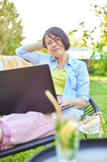 Freelance vrouw werkt op laptop thuis in de achtertuin