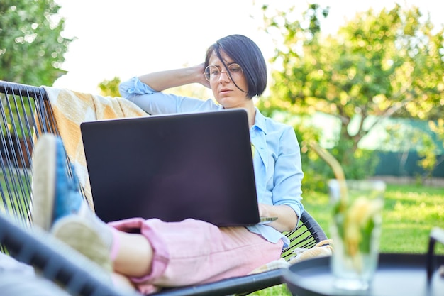 Freelance vrouw werkt op laptop thuis in de achtertuin